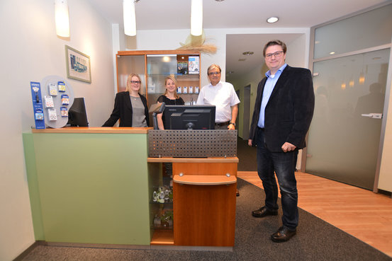 Empfangsbereich einer modernen Arztpraxis mit freundlichem Praxisteam und Patient.