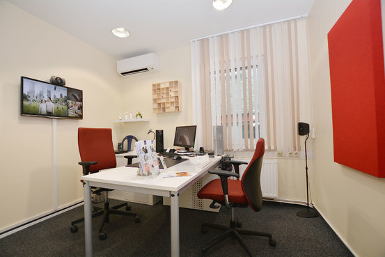 Modernes Büro mit zwei Schreibtischen, roten Bürostühlen und Computerarbeitsplätzen.